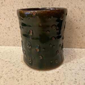 May include: A dark green ceramic mug with brown speckles and a textured surface.