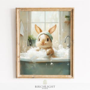 Puede incluir: Impresión enmarcada de un conejo en un baño de burbujas, con un gorro verde. La obra de arte tiene una paleta de colores pastel y está ambientada en un baño con una ventana. El marco es dorado.