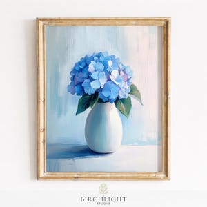 Könnte beinhalten: Gerahmtes Gemälde eines blauen Hortensienstraußes in einer weißen Vase. Das Kunstwerk zeigt einen hellblauen Hintergrund und einen goldfarbenen Rahmen. Das Gemälde ist unten mit "BIRCHLIGHT STUDIO" signiert.