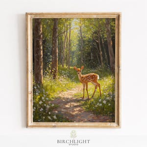 May include: A framed painting of a fawn in a sunlit forest. The artwork features a young deer with white spots standing on a path surrounded by trees and wildflowers. The painting has a vintage aesthetic with a gold-colored frame.
