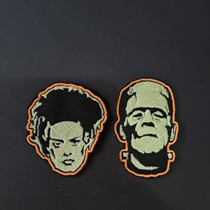 May include: Two embroidered patches featuring the faces of a female character with tall black hair and a male character with a flat-top head, both rendered in light green and black thread with a vibrant orange border outlining each individual shape.