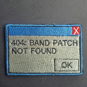 May include: A rectangular embroidered patch featuring a computer error message design. The patch has a blue top bar with a red X, a grey background, and black text that reads 404: BAND PATCH NOT FOUND, with an OK button in the bottom right corner.