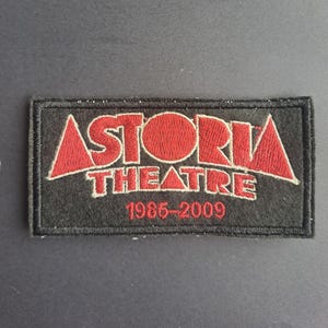 May include: A rectangular black embroidered patch featuring the red text ASTORIA THEATRE in a bold, stylised font. Below the main text, the years 1985-2009 are stitched in red thread. The entire patch is bordered by a thick black stitched edge.