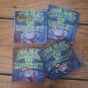 May include: Four square fabric patches featuring a blue background with yellow embroidered text that reads THIS IS MY CIRCUS AND MY MONKEY. Each patch displays an embroidered monkey wearing a red and yellow striped hat with its tongue sticking out.
