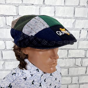 May include: A patchwork flat cap featuring various fabric panels in green, navy blue, and grey with herringbone and houndstooth patterns. The front panel displays the embroidered Guinness logo in white text with a gold harp icon above the lettering.