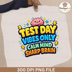 May include: A white graphic with the text "TEST DAY VIBES ONLY CALM MIND SHARP BRAIN" in yellow, blue, and green. A cartoon brain and lightning bolts are also featured. The image is held by a hand.