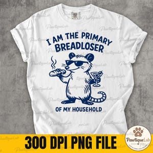 May include: A white short-sleeve t-shirt featuring a dark blue graphic of an opossum wearing sunglasses, holding a loaf of bread and a martini glass. The text reads I AM THE PRIMARY BREADLOSER OF MY HOUSEHOLD in dark blue capital letters.