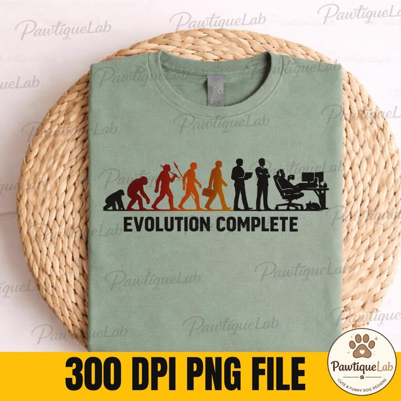 Pu&ograve; includere: Una t-shirt verde salvia con una stampa grafica che raffigura le fasi dell'evoluzione umana, passando da un primate a una persona seduta a una scrivania con computer. Il testo "EVOLUTION COMPLETE" &egrave; stampato in nero sotto la grafica.