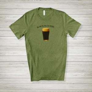 May include: Olive green t-shirt featuring the phrase "WHEN IN DOUBT" above a graphic of a pint of dark beer. The beer glass has a golden rim and a dark brown body. The shirt is made of a soft material.
