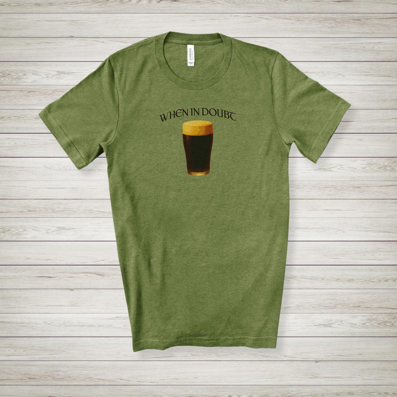 May include: Olive green t-shirt featuring the phrase "WHEN IN DOUBT" above a graphic of a pint of dark beer. The beer glass has a golden rim and a dark brown body. The shirt is made of a soft material.