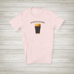 May include: Light pink t-shirt with the phrase "WHEN IN DOUBT" above a graphic of a pint of dark beer with a foamy head. The shirt is made of a soft material and has a crew neck.