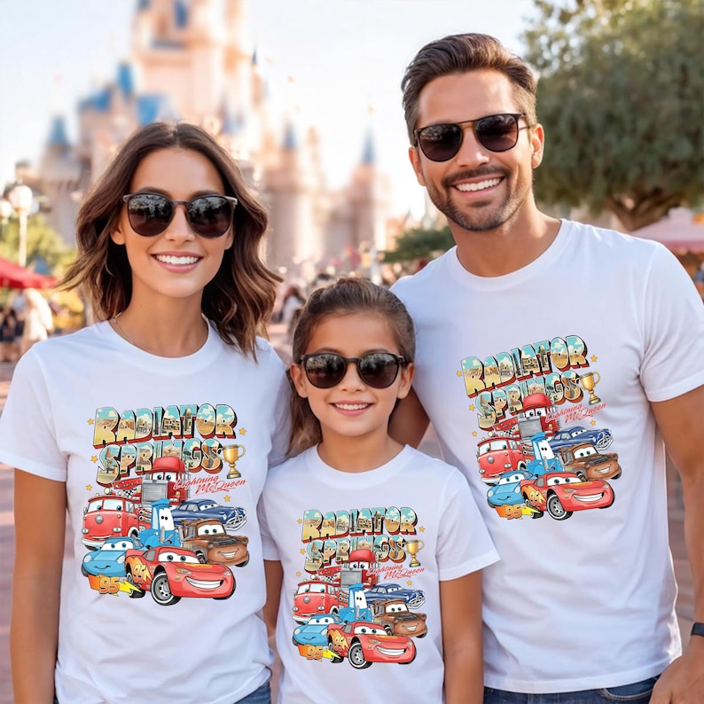 Peut inclure: T-shirts blancs avec un graphisme color&eacute; de personnages de Cars et le texte "Radiator Springs". Les chemises sont port&eacute;es par une famille de trois personnes, avec le texte et le graphisme au centre des chemises.