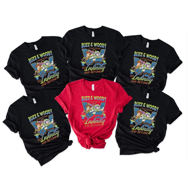 以下が含まれることがあります： 「Buzz & Woody Lightyear To Infinity And Beyond」のテキストと漫画のキャラクターが描かれた、黒と赤のTシャツのコレクション。青と緑の配色です。