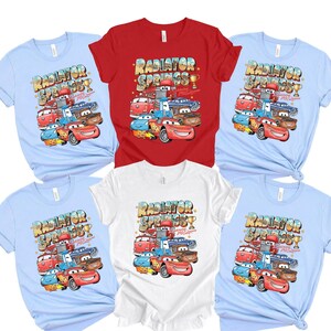 Peut inclure: Plusieurs t-shirts &agrave; manches courtes de couleurs bleu clair, rouge et blanc. Chaque t-shirt pr&eacute;sente un graphisme color&eacute; de voitures de dessins anim&eacute;s avec le texte "Radiator Springs" et "Lightning McQueen".
