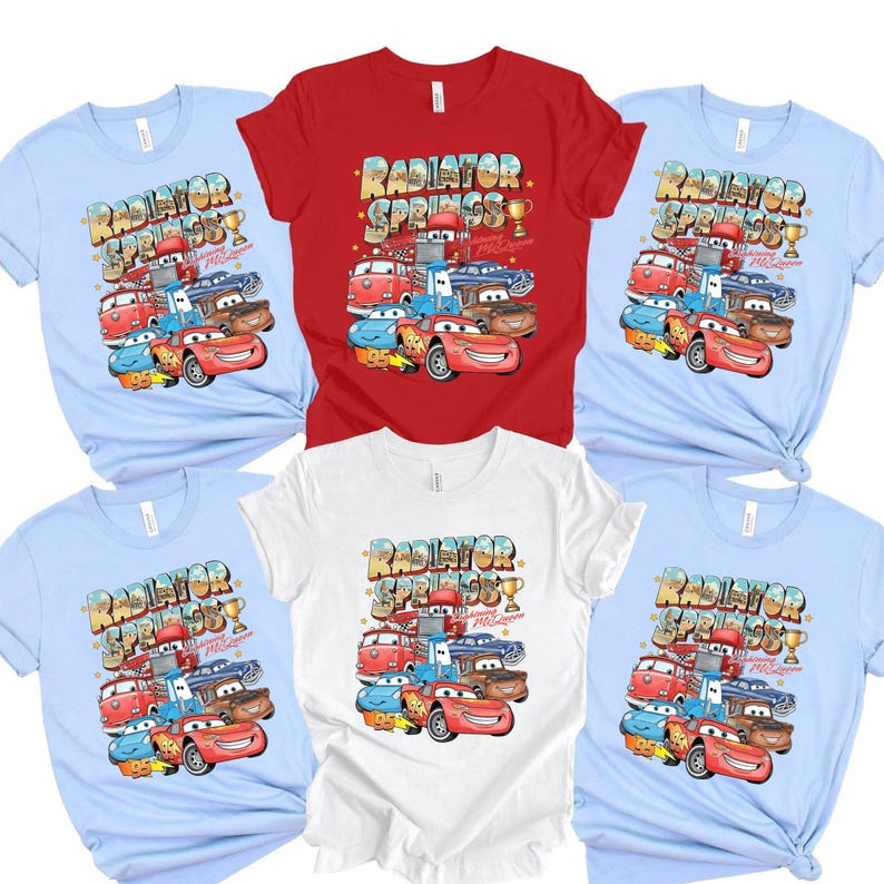 Peut inclure: Plusieurs t-shirts &agrave; manches courtes de couleurs bleu clair, rouge et blanc. Chaque t-shirt pr&eacute;sente un graphisme color&eacute; de voitures de dessins anim&eacute;s avec le texte "Radiator Springs" et "Lightning McQueen".