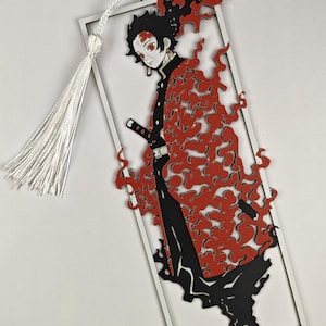 May include: A rectangular bookmark featuring a die-cut anime character with black hair and a red flame pattern on their clothing. The character is enclosed in a thin white frame and includes a white tassel attached to the top left corner.