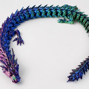 May include: An articulated dragon figurine featuring a metallic, iridescent finish that shifts between shades of deep blue, purple, and green. The creature has a segmented, flexible body with sharp, spiky scales along its back and four clawed limbs.