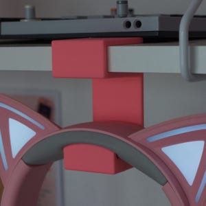 Könnte beinhalten: Ein korallenfarbener Kopfhörerständer, der an die Kante eines Regals geklemmt wird. Der Ständer verfügt über einen vertikalen Stützarm und eine geschwungene Halterung für einen rosa Kopfhörer mit Katzenohren, weißen Akzenten und grauem Polster.