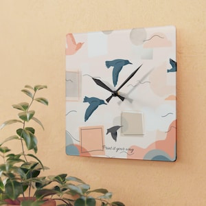 May include: Square wall clock with a pastel color scheme and a bird pattern. The clock face features illustrations of birds in flight, geometric shapes, and the text "Print it your way". The clock has black hands.