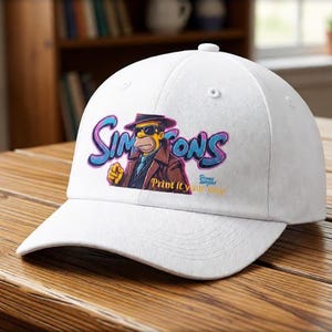 Puede incluir: Una gorra de béisbol blanca con una imagen de dibujos animados de un personaje de Los Simpson, con un sombrero fedora y una gabardina. La palabra "Simpsons" está escrita en azul y morado, con el texto "Print it your way" debajo.