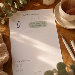 Può includere: Un foglio di carta bianco intitolato Number Practice con uno zero grande, una guida per tratti spessi e sottili e righe per esercitarsi con numeri e date. Il testo include Font Brittany, Press down = thick, Light stroke = thin e Take your time.