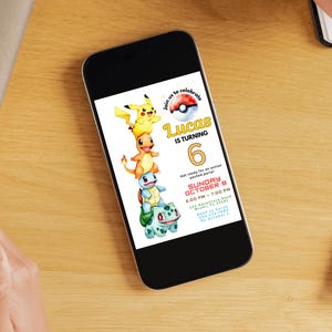 May include: A smartphone displays a birthday party invitation featuring stacked cartoon characters. The invitation reads "Lucas is turning 6" with event details. The phone rests on a wooden surface, with a coffee cup and stationery nearby.