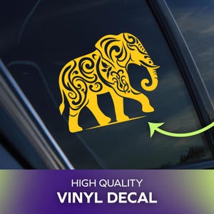 May include: A yellow vinyl decal featuring an elephant silhouette filled with intricate swirling patterns. The decal is applied to a dark glass surface. Below the decal, the text reads HIGH QUALITY VINYL DECAL in white capital letters.