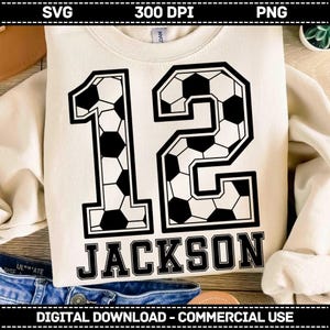 K&ouml;nnte beinhalten: Ein cremefarbenes Sweatshirt mit der gro&szlig;en Zahl 12, die in einem schwarz-wei&szlig;en Fu&szlig;ballmuster bedruckt ist. Unter der Zahl steht der Name JACKSON in fetten, schwarzen Gro&szlig;buchstaben. Das Design ist mittig auf der Vorderseite platziert.