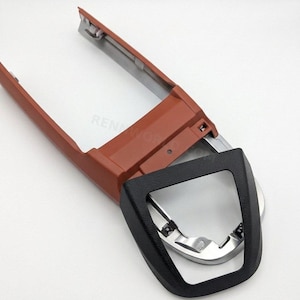 May include: A car interior trim piece with a reddish-brown frame and a black, textured bezel. The frame incorporates a silver metallic element. The text "RENNWORLD" is visible at the bottom.
