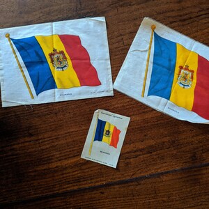 Könnte beinhalten: Drei Vintage-Stoff-Patches mit der rumänischen Flagge. Die Flagge ist blau, gelb und rot mit dem rumänischen Wappen in der Mitte. Die Patches befinden sich auf einer Holzoberfläche.