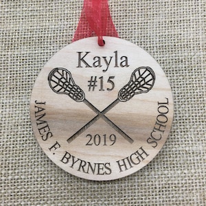 May include: A wooden lacrosse ornament with the name Kayla, number 15, and the text "James F. Byrnes High School 2019".