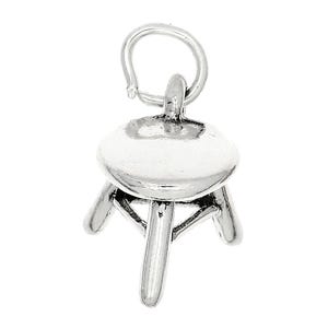 May include: A small, silver-colored charm in the shape of a three-legged stool. The charm has a round seat and three curved legs. A loop is attached to the top for easy attachment to a necklace or bracelet. The charm is made of a shiny metal.