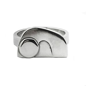 May include: A silver ring with a unique abstract design. The ring features a rounded shape with a smooth, polished finish.
