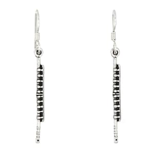 May include: A pair of silver dangle earrings featuring a flute design. The flute is made of small, round beads and has a silver hook.