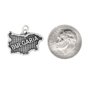 May include: Silver charm in the shape of Bulgaria with the word "BULGARIA" inscribed on it. The charm is about the size of a US dime.