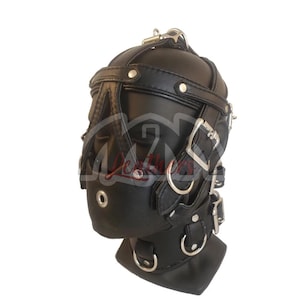 以下が含まれることがあります： 複数のストラップ、バックル、金属製Dリングが付いた黒い革のフード。フードにはノーズガードとあごストラップがあり、頭と顔の周りに一連のストラップとバックルが付いています。大人向けの製品です。