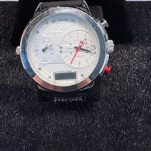 May include: A silver WEIDE sports watch with a white face and black strap. The watch has multiple dials, including a timer and date display. The watch is water resistant to 30m.