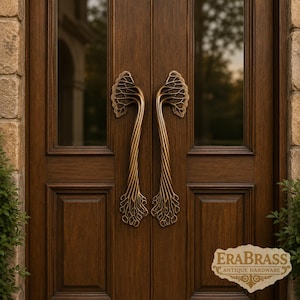 May include: A pair of vertical brass door handles with an intricate, organic tree-like design featuring branching patterns at the top and root-like structures at the bottom, mounted on a dark brown wooden double door with glass panels and EraBrass text.