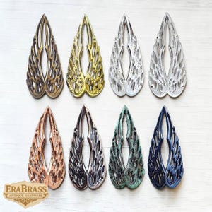 May include: Eight decorative metal wing-shaped ornaments in various colors, including bronze, gold, silver, copper, and teal. The wings have a detailed, openwork design. The EraBrass logo is visible in the lower left corner.
