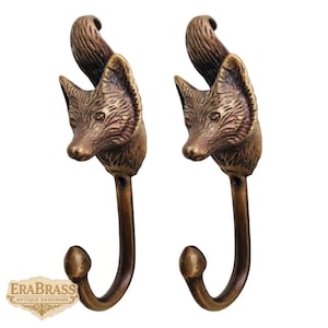 May include: Two antique brass fox head hooks. Each hook features a detailed fox head with a curved hook below. The hooks are a warm bronze color, perfect for adding a touch of rustic charm to any space.