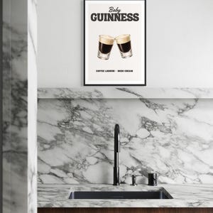 Puede incluir: Un cartel enmarcado con las palabras "Baby Guinness" encima de dos copas de c&oacute;ctel. El cartel tambi&eacute;n incluye el texto "Coffee Liqueur - Irish Cream". El cartel se muestra encima de un fregadero de cocina con un grifo negro y una encimera de m&aacute;rmol.