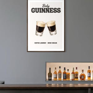 Puede incluir: Un p&oacute;ster enmarcado con dos chupitos de Baby Guinness, con licor de caf&eacute; y crema irlandesa. El p&oacute;ster muestra las palabras "Baby Guinness" en negrita, en letras negras. Debajo de la imagen, las palabras "Coffee Liqueur - Irish Cream" est&aacute;n impresas en negro.