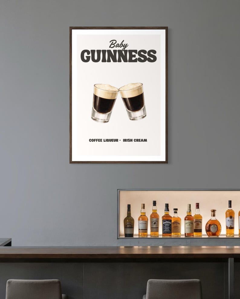 Puede incluir: Un p&oacute;ster enmarcado con dos chupitos de Baby Guinness, con licor de caf&eacute; y crema irlandesa. El p&oacute;ster muestra las palabras "Baby Guinness" en negrita, en letras negras. Debajo de la imagen, las palabras "Coffee Liqueur - Irish Cream" est&aacute;n impresas en negro.