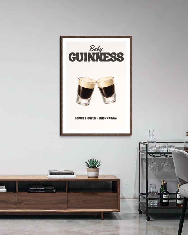 Puede incluir: Un p&oacute;ster enmarcado con una ilustraci&oacute;n del c&oacute;ctel "Baby Guinness". La imagen muestra dos vasos de chupito con licor de caf&eacute; y crema irlandesa en capas, con el texto "Baby Guinness" arriba y "Coffee Liqueur - Irish Cream" abajo.