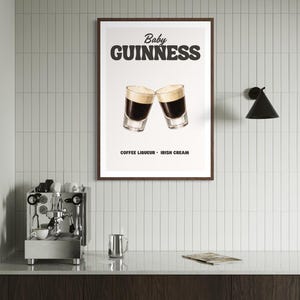 Puede incluir: Un cartel enmarcado con las palabras "Baby Guinness" sobre dos vasos de chupito llenos de un l&iacute;quido oscuro y cubiertos con espuma cremosa. El texto "Coffee Liqueur - Irish Cream" est&aacute; debajo. El cartel est&aacute; en una cocina.
