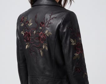 May include: A black leather motorcycle jacket featuring intricate embroidery on the back and sleeve. The design displays a winding snake intertwined with dark red roses, thorny branches, and green leaves, extending across the back panel and down the arm.