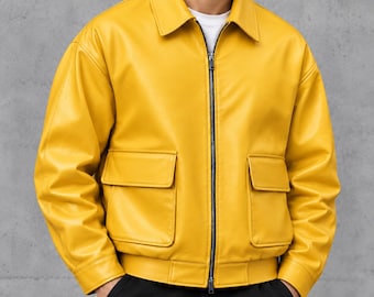 May include: A bright yellow jacket with a classic collar, a full-length front zipper, and two large flap pockets on the front. The jacket features long sleeves with cuffs and a hemmed waist, worn over a plain white shirt and black pants.