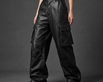 May include: Black leather cargo pants featuring a high-waisted design, a front button and zipper closure, and large side pockets on each leg. The pants have a loose, wide-leg fit with visible seam detailing and are paired with black boots.