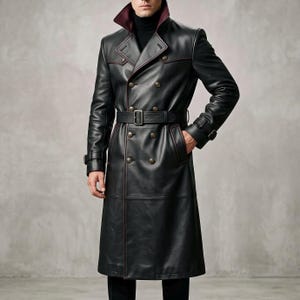 May include: A black leather trench coat featuring a double-breasted front with metallic buttons, a belted waist with a rectangular buckle, long sleeves with buckled cuffs, and a high collar with a dark red interior lining.