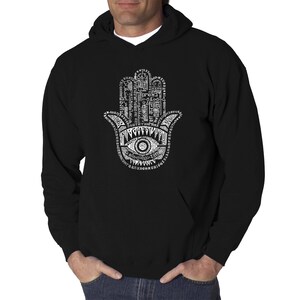 May include: Black hooded sweatshirt with a white graphic of the Hamsa hand, a symbol of protection and good luck, made up of words and symbols.